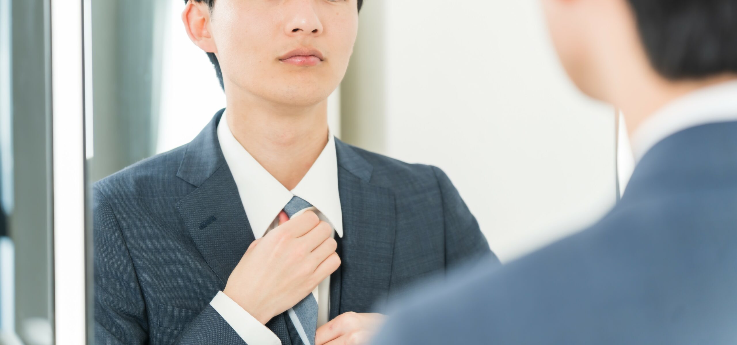 鏡で身だしなみをチェックする男性